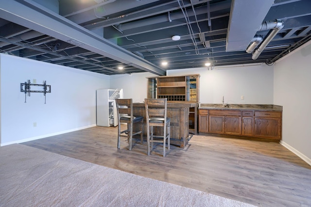 bar featuring baseboards, light wood-style floors, a sink, and wet bar