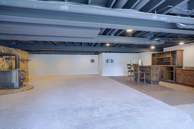 below grade area featuring a wood stove, a bar, and wood finished floors