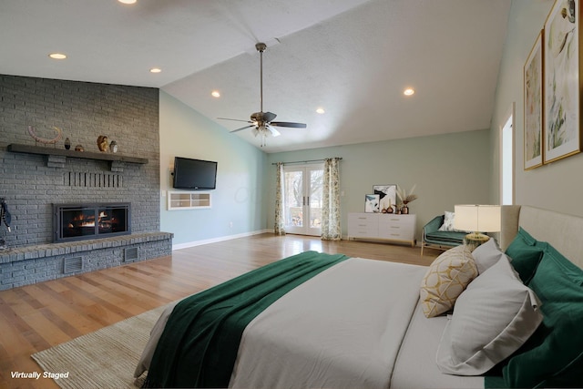 bedroom with ceiling fan, wood finished floors, vaulted ceiling, french doors, and a fireplace