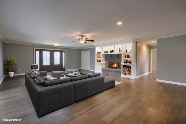 living room featuring ornamental molding, baseboards, a fireplace, and hardwood / wood-style floors