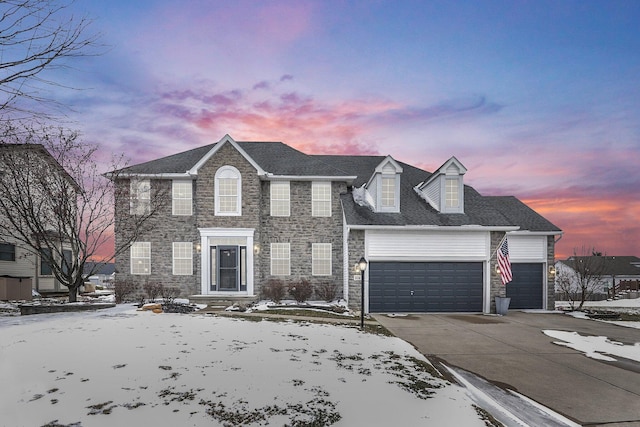 colonial inspired home with stone siding, driveway, and an attached garage