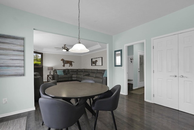 dining area with dark wood-style floors, a raised ceiling, and baseboards