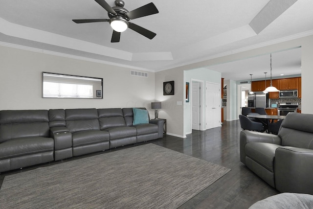 living area featuring ornamental molding, a tray ceiling, visible vents, and dark wood finished floors