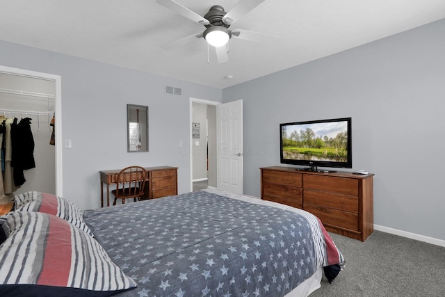 bedroom with baseboards, visible vents, a ceiling fan, a walk in closet, and carpet floors