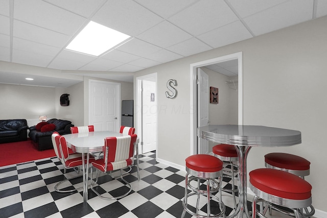 dining room with a paneled ceiling, baseboards, and tile patterned floors