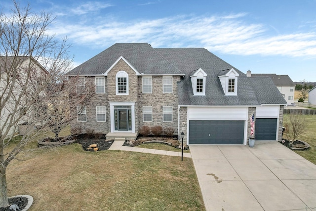 colonial inspired home with an attached garage, concrete driveway, stone siding, roof with shingles, and a front yard