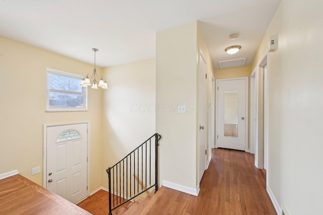 foyer entrance featuring a chandelier, baseboards, and wood finished floors