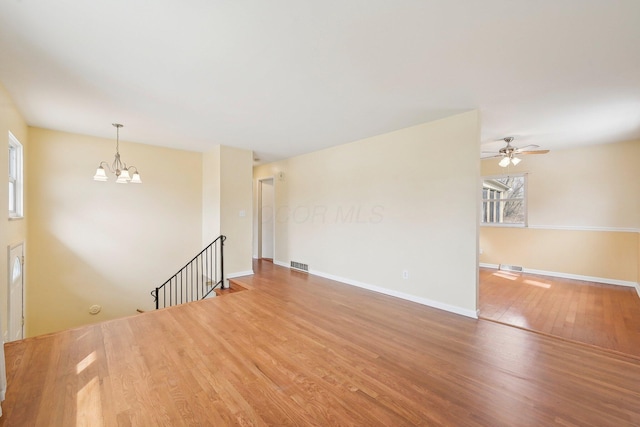 unfurnished room with a healthy amount of sunlight, baseboards, visible vents, and wood finished floors