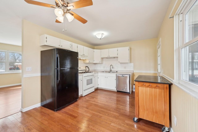 kitchen featuring dishwasher, light wood-style floors, freestanding refrigerator, under cabinet range hood, and gas range gas stove