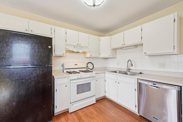 kitchen with white gas stove, under cabinet range hood, a sink, stainless steel dishwasher, and freestanding refrigerator