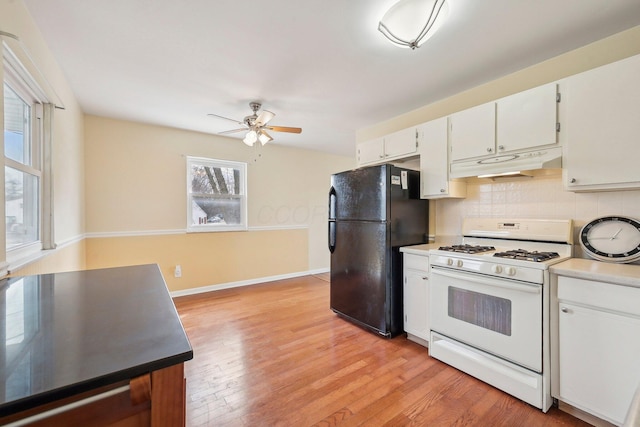 kitchen featuring light wood-style flooring, freestanding refrigerator, under cabinet range hood, and white gas range