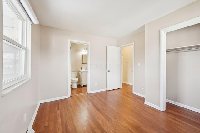 unfurnished bedroom featuring multiple windows, baseboards, and wood finished floors