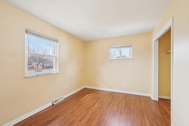 unfurnished bedroom featuring a closet, wood finished floors, visible vents, and baseboards