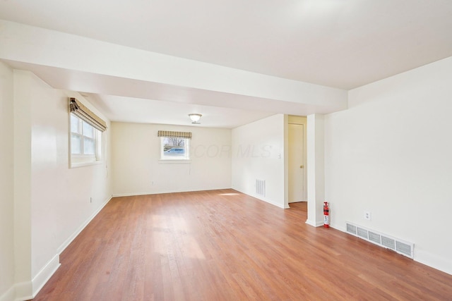 empty room featuring visible vents, light wood-style flooring, and baseboards