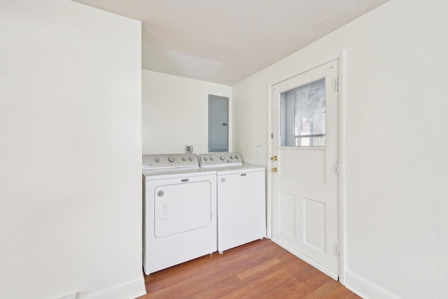 washroom with laundry area, separate washer and dryer, light wood-style flooring, and electric panel