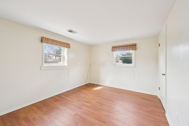 unfurnished room with plenty of natural light, visible vents, light wood-style flooring, and baseboards