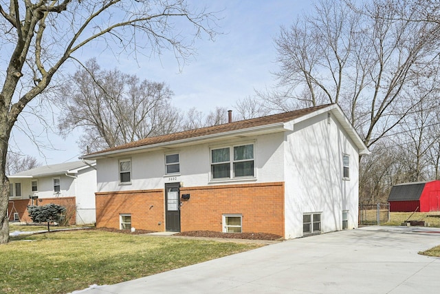 view of front facade with concrete driveway, brick siding, fence, and a front lawn