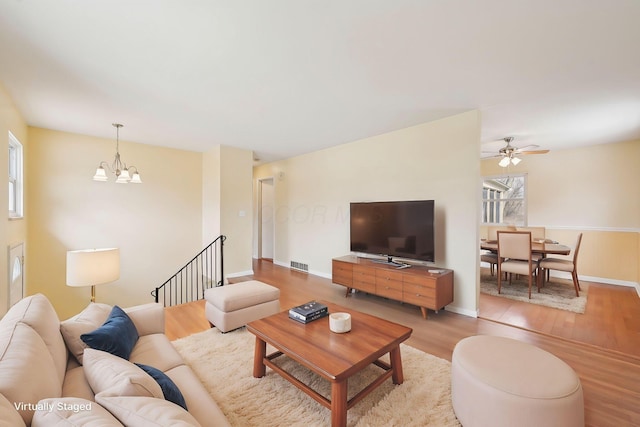 living room with visible vents, light wood-style flooring, baseboards, and an inviting chandelier