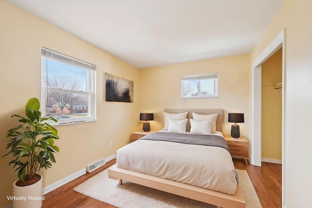 bedroom with visible vents, baseboards, and wood finished floors