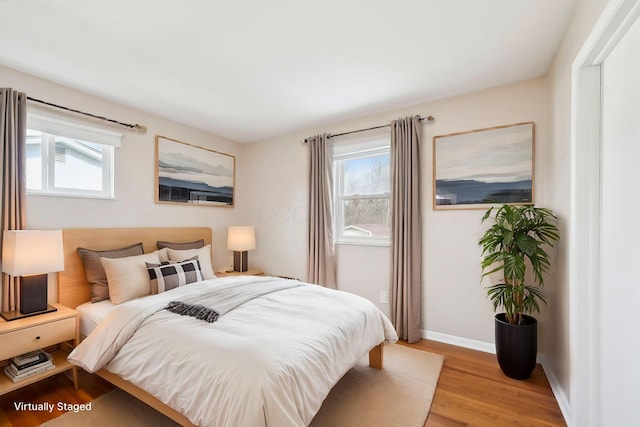 bedroom with multiple windows, light wood-style flooring, and baseboards