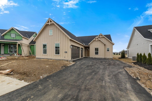 view of front of house featuring driveway, a garage, central AC, and board and batten siding