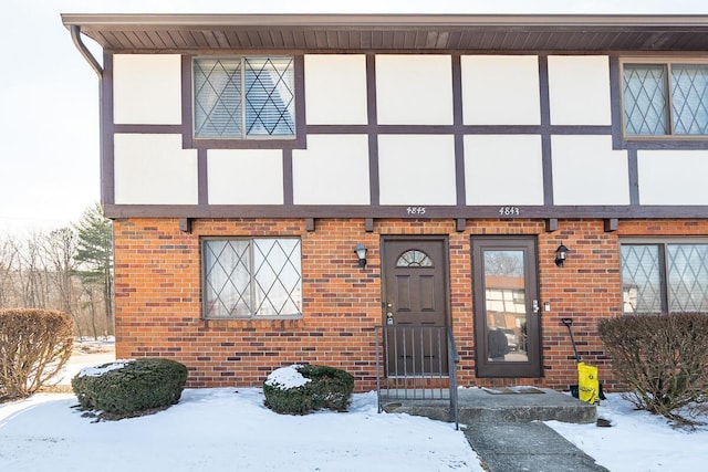 snow covered property entrance with brick siding