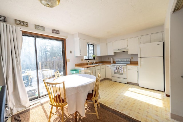 kitchen featuring under cabinet range hood, white appliances, a sink, white cabinets, and light floors