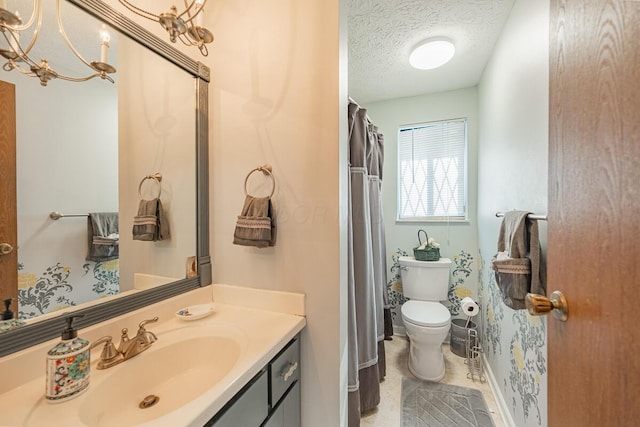 bathroom with baseboards, a textured ceiling, toilet, and vanity