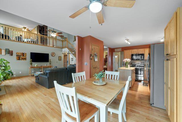 dining space featuring stairway, light wood-style flooring, and a ceiling fan