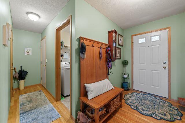 foyer featuring light wood-style floors, washer / clothes dryer, and a textured ceiling