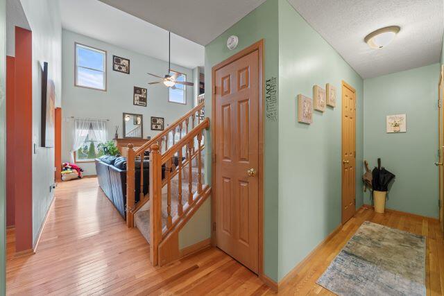 hallway with light wood-style flooring, stairs, and baseboards