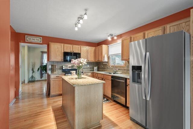 kitchen featuring appliances with stainless steel finishes, light wood-style floors, a kitchen island, and light stone countertops