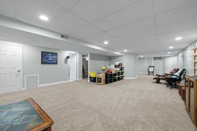 interior space featuring a drop ceiling, recessed lighting, carpet flooring, visible vents, and baseboards