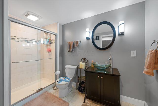 bathroom with toilet, a shower stall, baseboards, and vanity