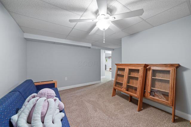 sitting room with carpet, a drop ceiling, ceiling fan, and baseboards