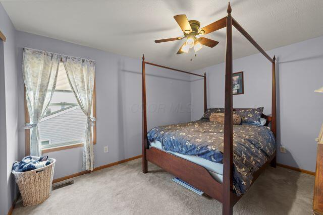 carpeted bedroom featuring ceiling fan, visible vents, and baseboards