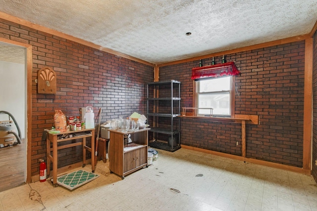 miscellaneous room with a textured ceiling, brick wall, and light floors