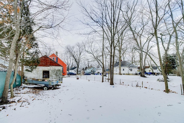 yard layered in snow featuring a garage, fence, and a residential view