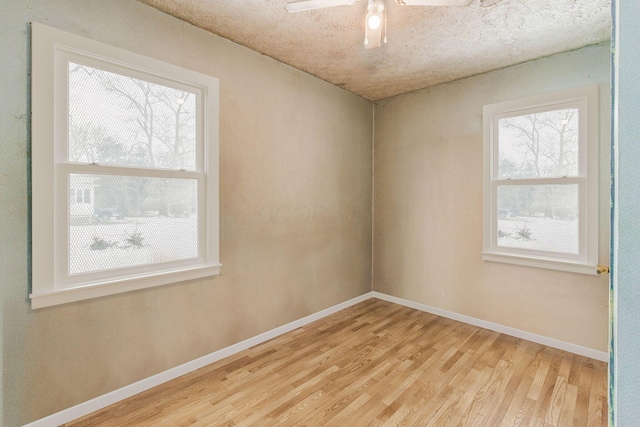 unfurnished room featuring a ceiling fan, light wood-style flooring, and baseboards