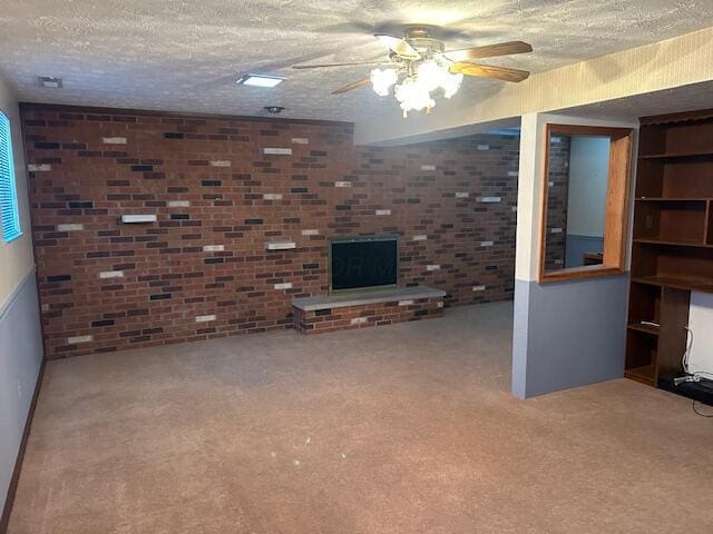 unfurnished living room featuring a textured ceiling, brick wall, carpet, and a ceiling fan