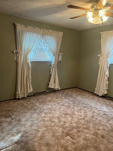 unfurnished room featuring carpet, visible vents, and a wealth of natural light