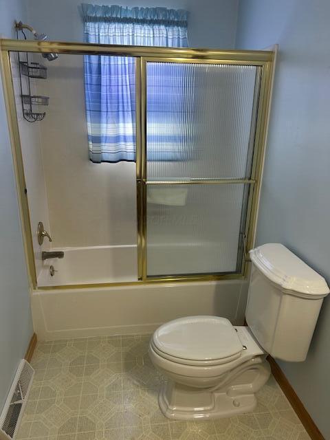 full bath with visible vents, toilet, combined bath / shower with glass door, tile patterned flooring, and baseboards