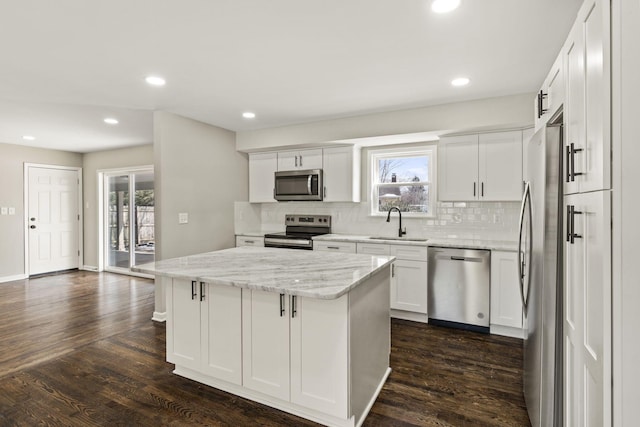 kitchen featuring tasteful backsplash, a sink, a kitchen island, appliances with stainless steel finishes, and dark wood-style flooring