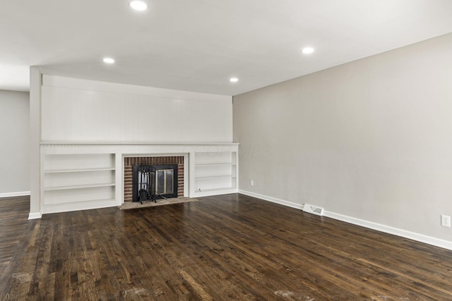 unfurnished living room with visible vents, a brick fireplace, dark wood-type flooring, baseboards, and recessed lighting