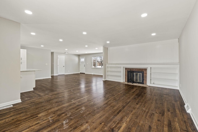 unfurnished living room featuring dark wood finished floors, recessed lighting, a fireplace, and built in features