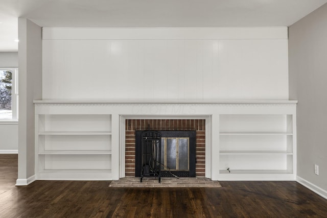 interior details featuring a brick fireplace, built in features, wood finished floors, and baseboards