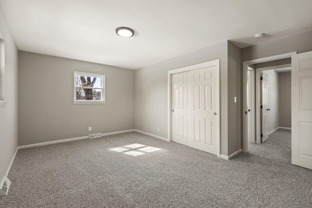 unfurnished bedroom featuring a closet, visible vents, baseboards, and carpet floors