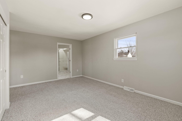 unfurnished bedroom featuring carpet, visible vents, baseboards, a closet, and connected bathroom