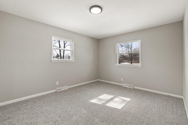 carpeted empty room with visible vents, a healthy amount of sunlight, and baseboards