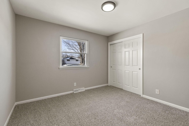 unfurnished bedroom featuring visible vents, baseboards, carpet, and a closet